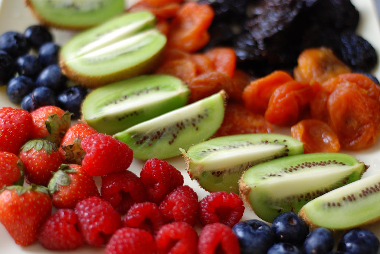 Vibrant selection of fresh berries, kiwi, and dried fruits in an artistic arrangement.