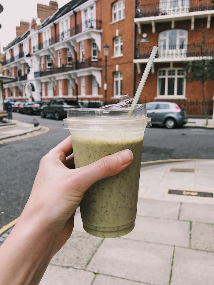 Crafting Captivating Headlines: Your awesome post title goes here Hand holding a green smoothie in a disposable cup on a street in Greater London, UK.